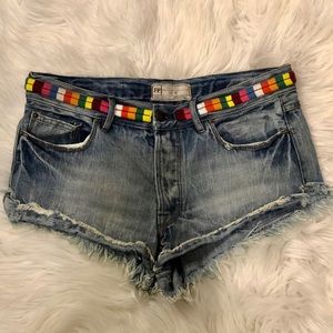 Free People distressed denim shorts with colorful stitch detailing